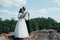 Wedding photo of a bearded groom with glasses in a gray jacket and a bride on a rock