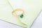 Wedding ring with emerald green gemstone on greenery envelope