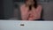 Wedding ring on table, crying woman on background, couple breakup, divorce