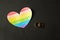 Wedding rings on a black background and a heart in the form of a flag lgbt, same-sex marriage, homosexuality