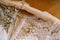 Wedding rings and an engagement ring white wedding dress of the bride with lace and wildflowers on a wooden table.