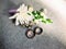 Wedding rings with groom`s boutonniere, white, purple and green floral decorations on grey background. Wedding blog concept