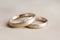 Wedding rings lie on greyish beige