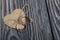 Wedding rings tied with a rope. Lying on a heart cut out of paper. On brushed pine boards painted in black and white