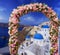 Wedding at Santorini. Beautiful arch decorated with flowers of roses with  blue church of Oia, Santorini, Greece at most romantic