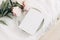 Wedding still life scene. White empty book cover mockup on marble tray. Pink peony flowers on white linen table cloth