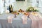A wedding table for newlyweds groom and bride decorated with flowers and a tablecloth in a designer style with food and drinks.