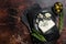 Wedge of Roquefort cheese in a steel plate with olives and herbs. Dark background. Top view. Copy space