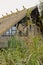 Weeds before steel-structured building with pitched and thatched roof