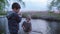 Weekend in open, little boys steal fishing rods entering while standing on a pier by the river among reeds