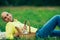 Weekend picnic concept. Portrait of a young handsome bald man in trendy clothes lying on green grass in the park. Picnic basket