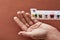 A weekly medicine dispenser opened for Sunday, hand taking pills and vitamins out of white pill box on terracotta