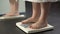 Weight problems, lady standing on scales at home to check weight, extra fat