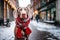 Weimaraner dog wearing a red Christmas scarf against the backdrop of a city street decorated for Christmas and a Christmas market