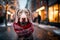 Weimaraner dog wearing a red Christmas scarf against the backdrop of a city street decorated for Christmas and a Christmas market