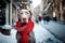 Weimaraner dog wearing a red Christmas scarf against the backdrop of a city street decorated for Christmas and a Christmas market