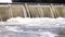 Weir on the Odra river in Wroclaw, Poland. Water in motion forming foam and vortexes on the base of waterfall