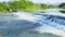 Weir in river, water flowing down from barrier to lower level