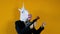 Weird funny video - business woman in a suit with unicorn head holding a gun over yellow background