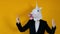 Weird funny video - woman in a suit with unicorn head dancing over yellow background