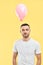 Weird young man with pink air balloon on his neck over yellow background