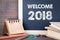 Welcome 2018. paper calendar and chalkboard on a wooden table