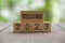 Welcome 2023 text engraved on wooden blocks with blurred park background. New year concept