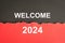 Welcome 2024, word on black and red torn paper