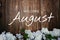 Welcome August text and blue flower decoration on wooden background