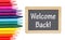 Welcome Back message on a chalkboard with colored watercolor pencils