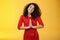 Welcome come inside. Portrait of friendly and polite good-looking female host in red dress with curly hair holding hands