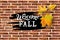 Welcome Fall handwriting lettering with falling leaves on brick wall