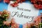 Welcome February text with Pink Flower frame on blue background