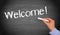 Welcome - female hand writing text on chalkboard