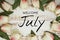 Welcome July text and tulip flower decoration on wooden background