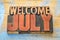 Welcome July word abstract in wood type