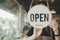 Welcome. Open. barista, waitress woman turning open sign board on glass door in modern cafe coffee shop