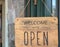 Welcome, we are open sign on the door of the store/cafe. Wooden board with text. Business after quarantine concept.