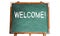 Welcome! text message in white chalk written on a school green old grungy vintage wooden chalkboard or blackboard