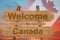 Welcome to Canada sing on wood background with blending national flag