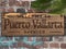 Welcome to Puerto Vallarta Mexico Wood Plaque on brick wall with palm tree leaf and graffiti