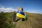 Welcome to Ukraine. Two brothers hold ukrainian flag near big stone in hill Pidkamin