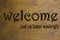 Welcome we`ve been waiting sign set on a wood background. Brown 3D text against wood grain background.