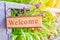 Welcome wooden label in front of the door on natural background