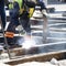 Welder construction worker working on city street crossroad, replacing old rotten tram rails with new once and arc welding them