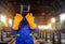 Welder in orange gloves and mask standing in factory