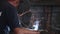 Welder in protective mask makes electric arc welding of metal in slow motion.