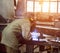 Welder in protective suit at the factory welds parts, workshop, sunset