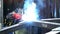 Welder with torch and protective helmet making bright sparks during welding