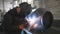 Welder welding metal construction at industrial metalworking production. Worker in protective mask doing joint between